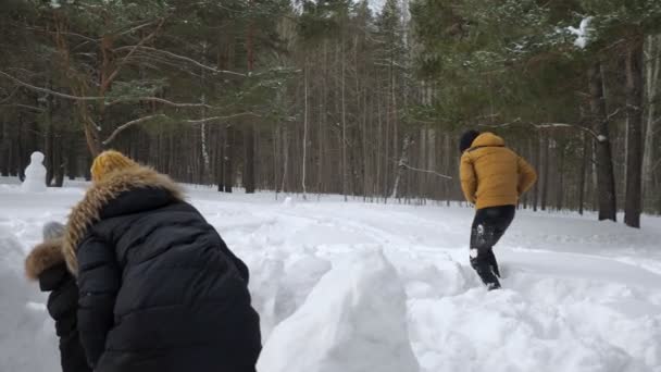 男は雪の壁の前に隠れて彼の家族、妻と小さな息子と雪玉を遊んでいます. — ストック動画