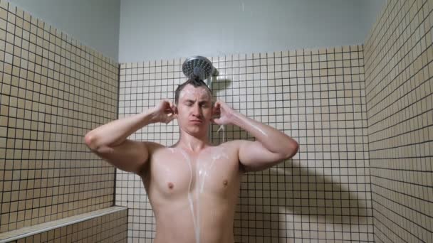 Retrato de un joven en estado de ánimo juguetón está tomando una ducha y lavándose la cabeza . — Vídeo de stock