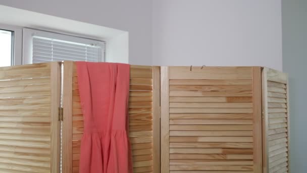 Lady changes clothes and hangs on wooden screen in boutique — Stock Video