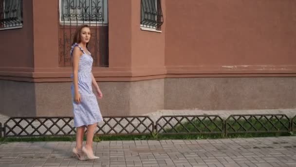 Slim european model in trendy blue dress walks along street — Stock Video