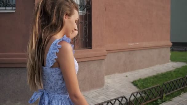 Slank Europees model in trendy blauwe jurk loopt langs de straat — Stockvideo