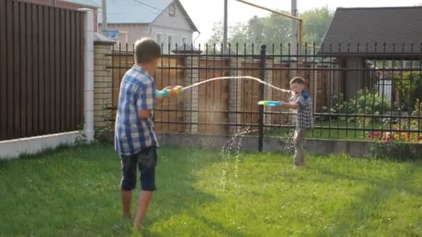 Niños con camisas a cuadros y pantalones cortos juegan con pistolas de agua — Vídeos de Stock
