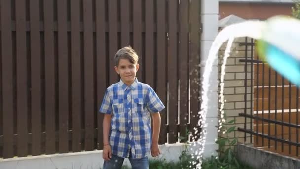 Schattig school jongen geniet druppels stroomt van water gun Jet — Stockvideo