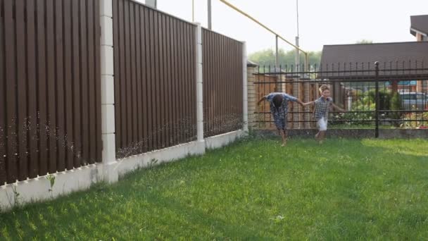 Счастливые маленькие братья наслаждаются жизнью и бегают по зеленому саду — стоковое видео
