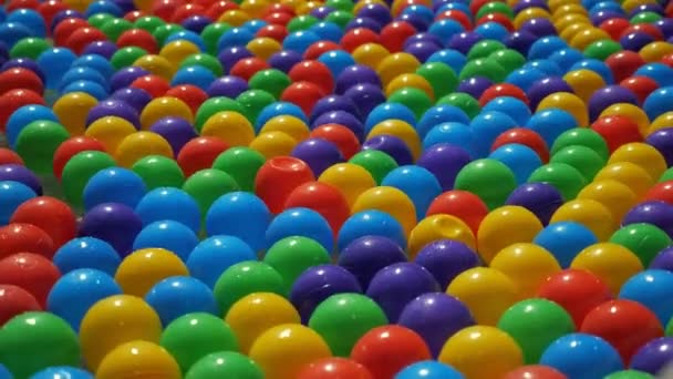 Красочные маленькие пластиковые шарики, плавающие и движущиеся в воде, вид крупным планом . — стоковое видео