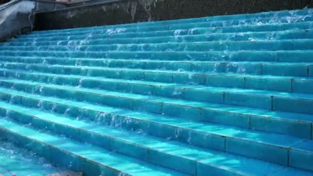 El agua fluye por los escalones de cerámica azul en la fuente en el parque de la ciudad . — Vídeos de Stock