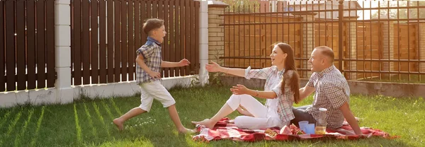 Žena a pohledný muž sedí na dvoře a syn skáče po matce — Stock fotografie