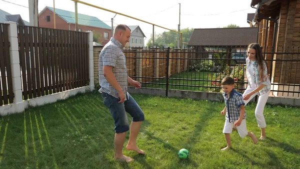 Foreldre liker å spille fotball med aktiv gutt på plenen – stockfoto