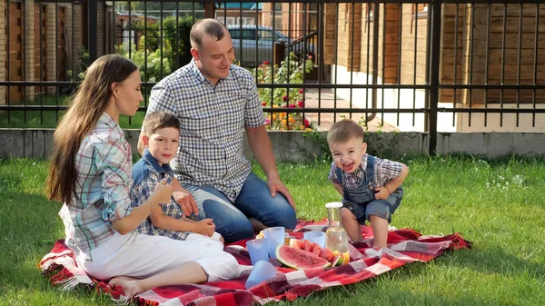 Boldog család ül a takaró és az apa Önt narancslé — Stock Fotó