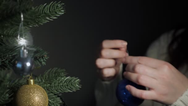 Dama lleva a cabo decoraciones de Navidad y se pone en el árbol artificial — Vídeo de stock