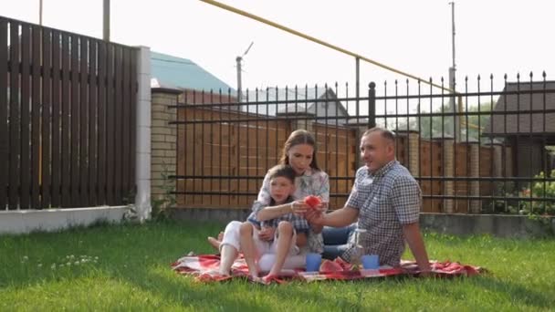 Happy young woman and man sit with little boy on lawn — Stock Video