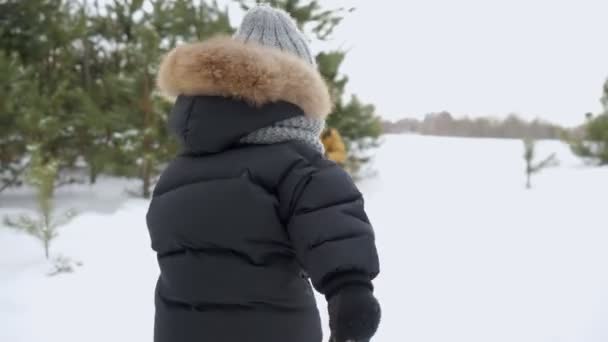 Chlapeček v teplých šatech běží ke svým rodičům a mazlí si je v zimním lese.. — Stock video