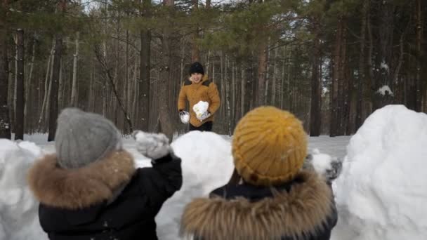 L'uomo sta giocando palle di neve con la sua famiglia, moglie e piccolo figlio nascosto davanti al muro di neve . — Video Stock