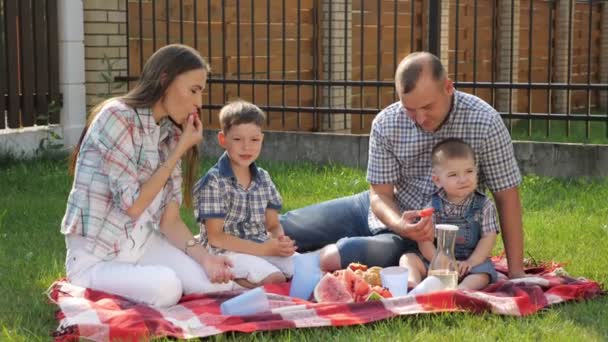 Mor med brunt hår sitter med stilig far och pojkar — Stockvideo