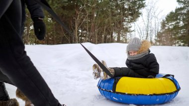 Mutlu anne-babalar kış parkında tüp oğulları çalışan ve sürgülü.