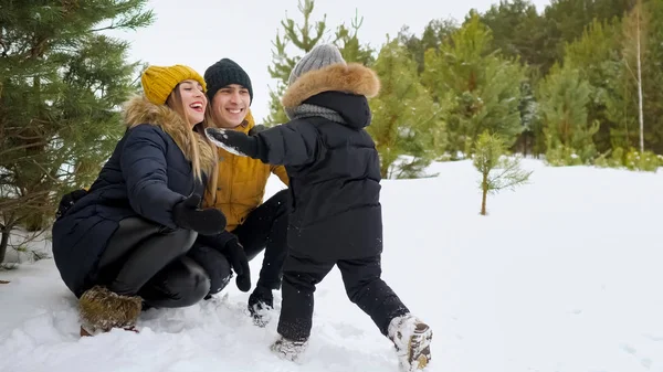 Menino com uma corrida corre para os braços de seus pais e os deixa cair na neve . — Fotografia de Stock