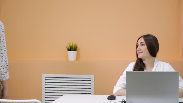 Morena se sienta en la mesa marrón joven mujer viene y habla — Vídeos de Stock