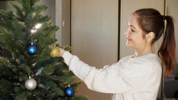 Lächelnde junge Frau mit Pferdeschwanz schmückt Weihnachtsbaum — Stockfoto