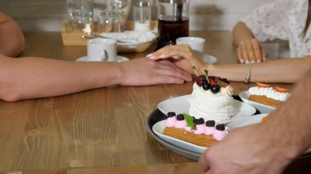 Кондитер подает вкусные торты для пары в кафе — стоковое видео