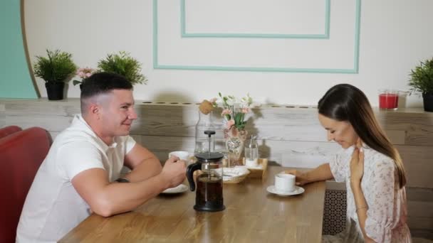 Les jeunes parlent et boivent du thé à une table en bois dans un café — Video