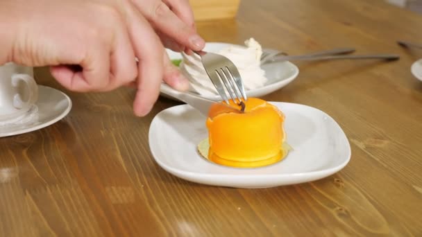Молодой человек режет яблочный торт на белой тарелке за столом — стоковое видео