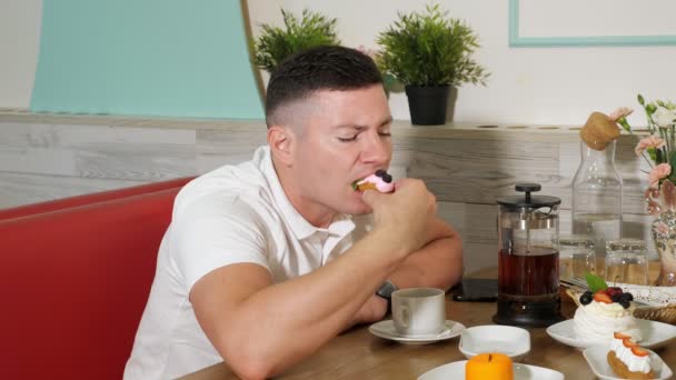 Mann isst leckeren Kuchen mit Sahne und Beeren in Süßwarenladen — Stockvideo