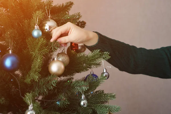 Mains féminines tenir et accrocher la boule de jouet d'or sur l'arbre de Noël — Photo