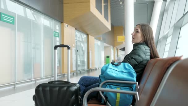 Joven mujer cansada está esperando su vuelo en el aeropuerto sentado en el pasillo . — Vídeos de Stock