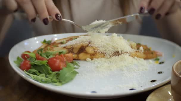 Krásná žena je jídelní palačinky se šunkou, sýrem, zelení a rajčaty. — Stock video