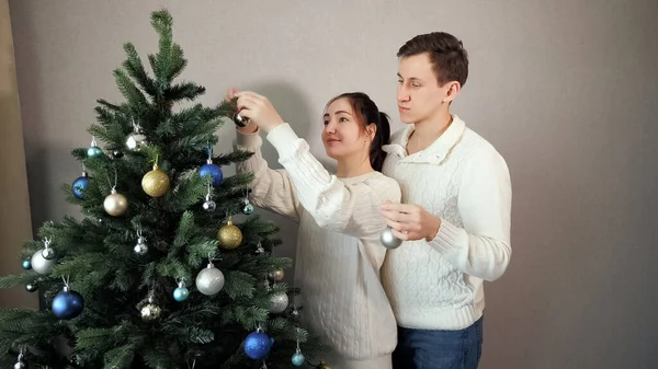 Hombre está detrás de señora ayuda a decorar árbol de Navidad — Foto de Stock