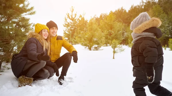 Menino com uma corrida corre para os braços de seus pais e os deixa cair na neve . — Fotografia de Stock