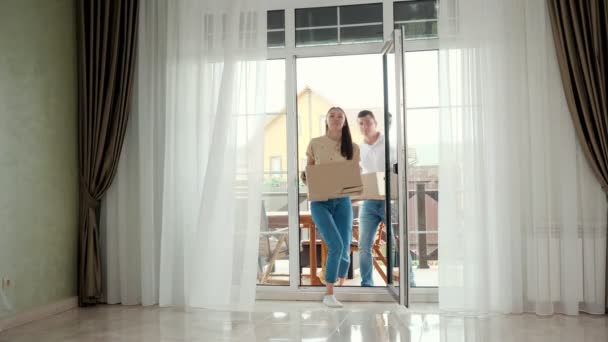 Pár nošení džíny vstupuje do nového domu sklo panoramatické dveře — Stock video