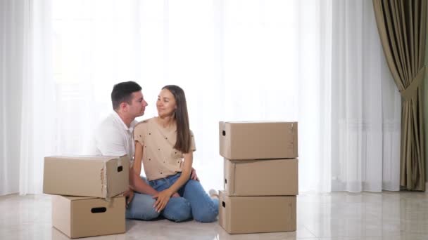 Son pops up from behind boxes near parents sitting on floor — ストック動画