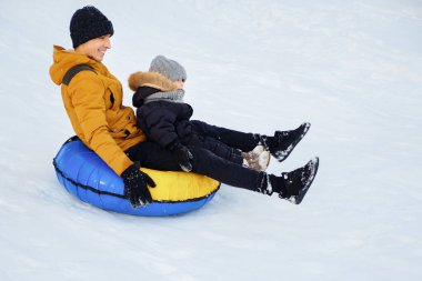 Mutlu baba ve oğlu tüp de kar tepeden kayıyor.