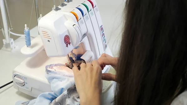 Overlok bez kenarlarında atölye atölyesinde dikiş terzisi, eller closeup.