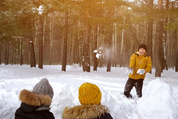 Mamá, hijo y papá están jugando a las bolas de nieve en el bosque de invierno. Fin de semana familiar . — Foto de Stock