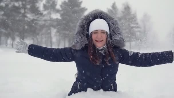 Mujer feliz sentada en una nieve. Paseos alegres en el parque de invierno — Vídeos de Stock