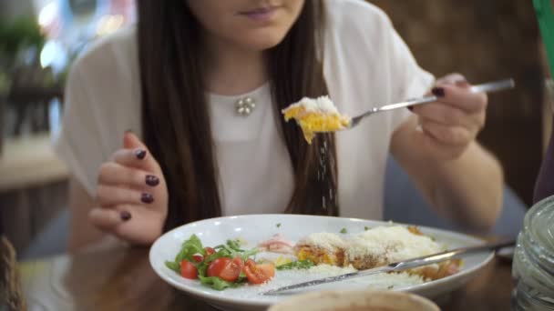 Hermosa chica come panqueques con jamón, queso, verduras y tomates en la cafetería — Vídeos de Stock