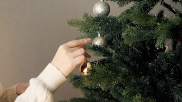 Dame hält Weihnachtsschmuck in der Hand und setzt künstlichen Baum auf — Stockvideo