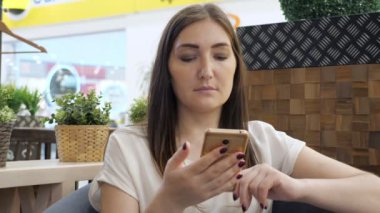 Güzel kız, kafedeki akıllı telefondan bakar.