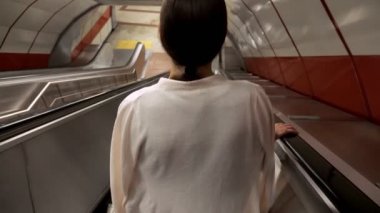 Kadın şehir metrosuna çıkmak için uzun yürüyen merdiven kullanıyor.