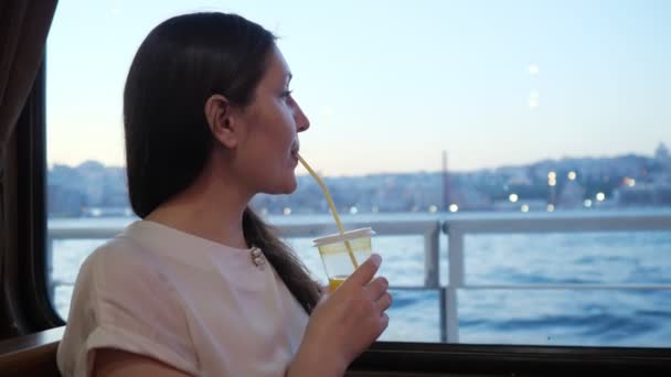 Dame boit une boisson et regarde de loin profiter du voyage — Video