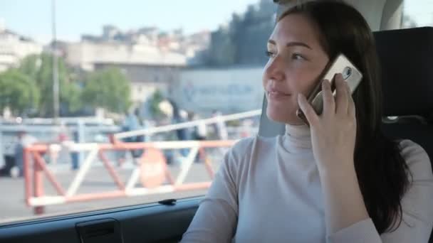 Frau spricht mit Smartphone und lächelt beim Autofahren — Stockvideo