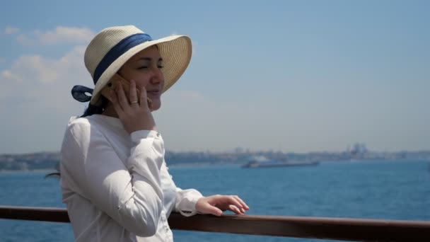 Lady travels by ship and talks on phone standing on deck — Stock Video