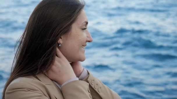 Kobieta dotyka włosów korzystających z pięknej przyrody przeciwko morzu — Wideo stockowe