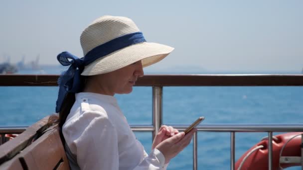 Mujer se para en la cubierta del barco y navega por Internet contra yates — Vídeo de stock