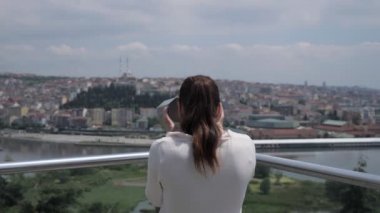 Kadın körfez boyunca şehri keşfetmek için dürbünle bakıyor.