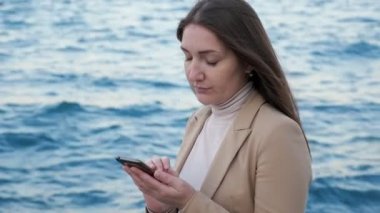 Kız sahilde durur ve arkadaşlarıyla denize karşı sohbet eder.