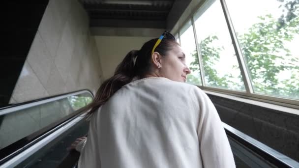Brunetka lady jedzie w górę schody ruchome dla podróżujących na kolejce linowej — Wideo stockowe