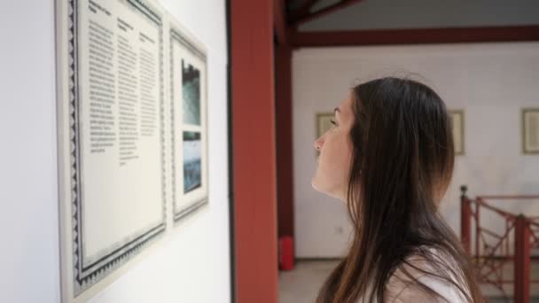 Frau steht mit halbem Gesicht im Museum und liest Informationen — Stockvideo